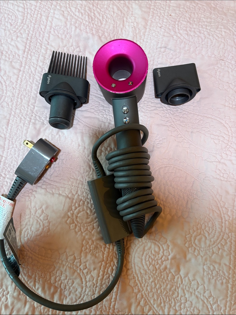Dyson hair dryer in fuchsia pink and dark gray with attachments